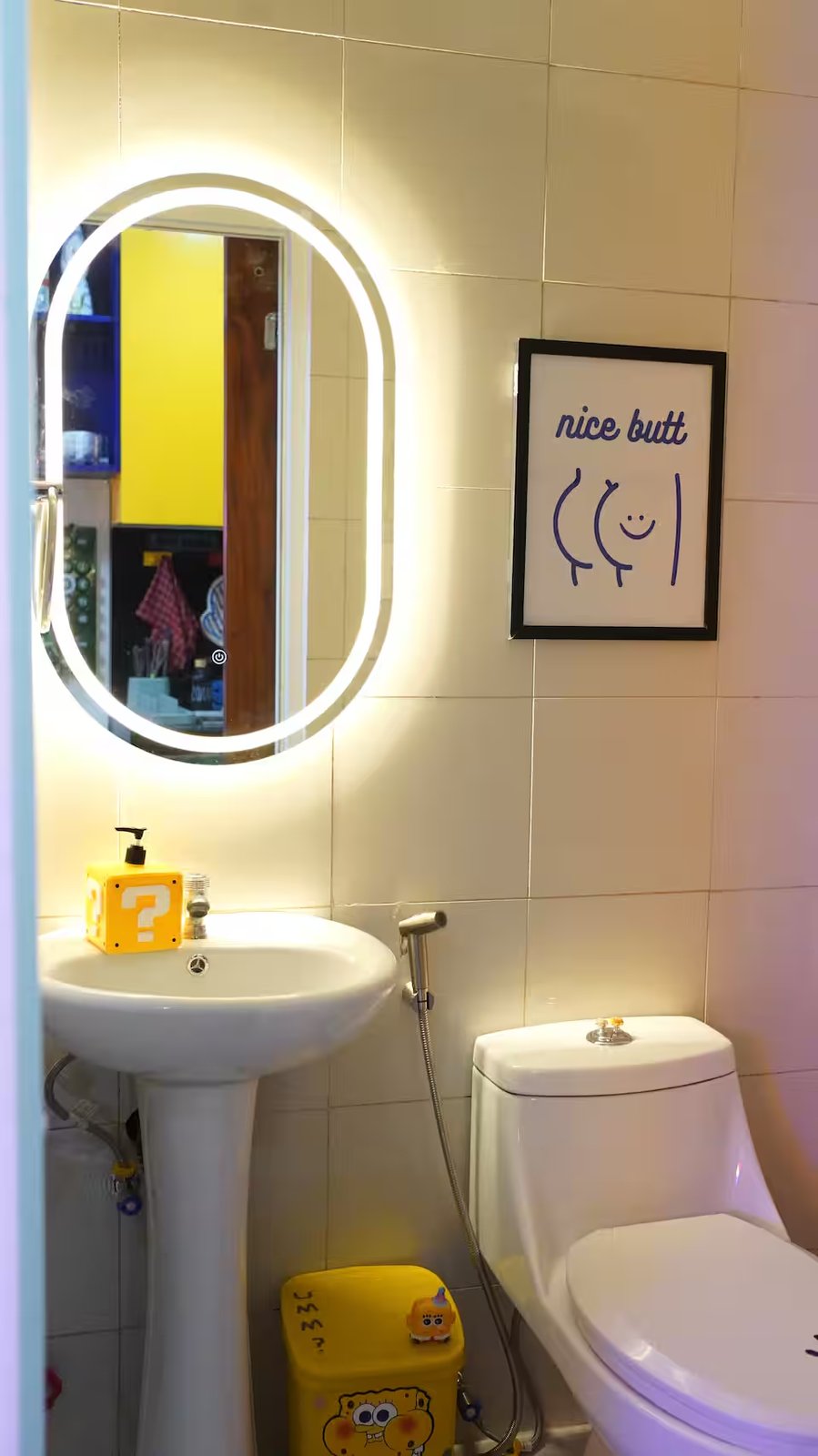 Bathroom oval LED mirror, white pedestal sink and Spongebob trash bin