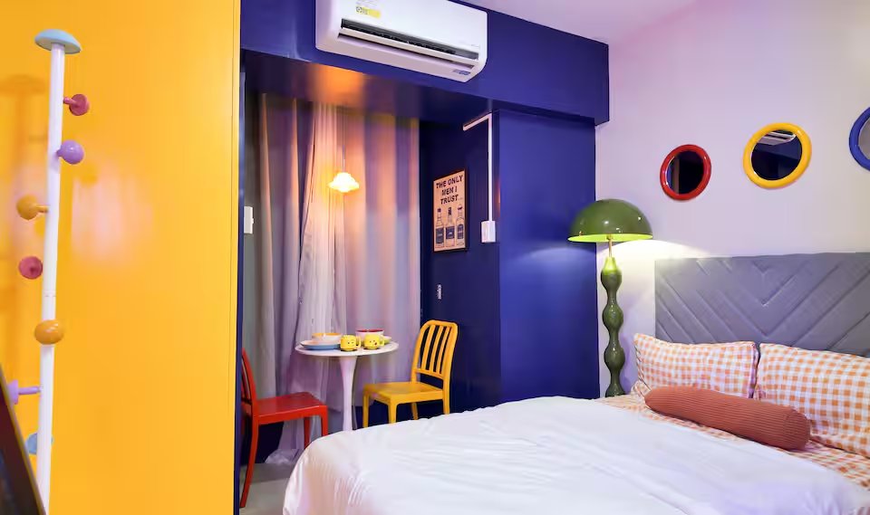 Bedroom cobalt blue accent wall with red and yellow circle mirrors, green dome lamp and double bed