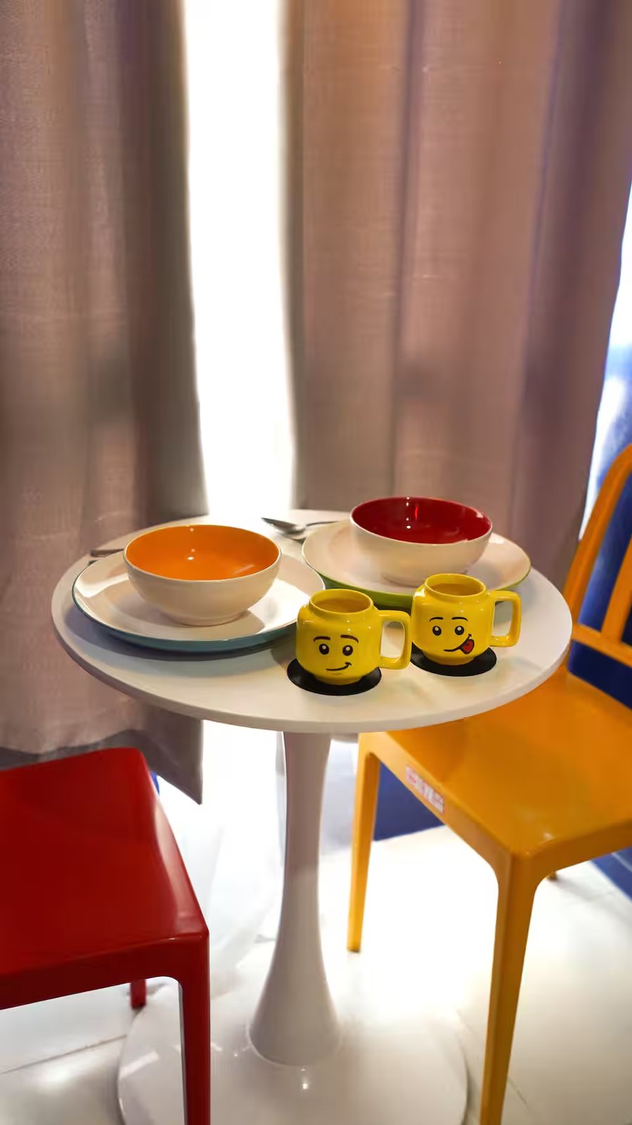 Lego minifigure head mugs and breakfast bowls arranged on white tulip table