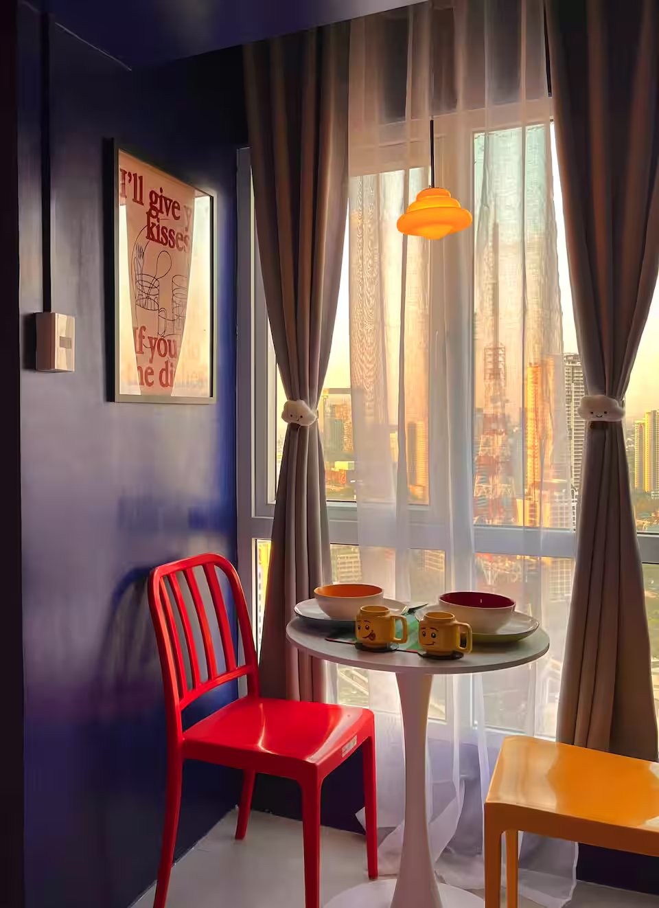 Tulip table with red chair beside floor-to-ceiling window catching golden Quezon City sunset