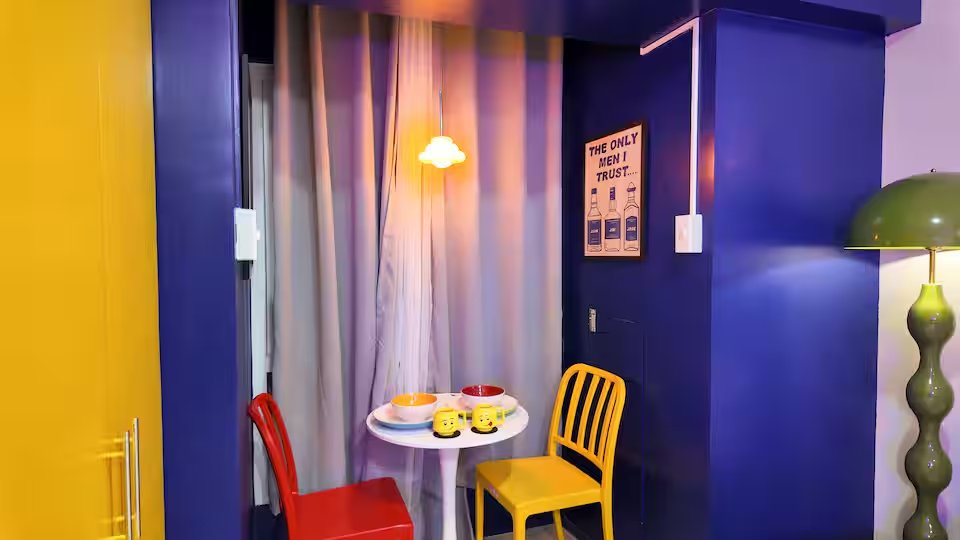 Dining nook with yellow and red chairs, cloud pendant lamp and cobalt blue wall