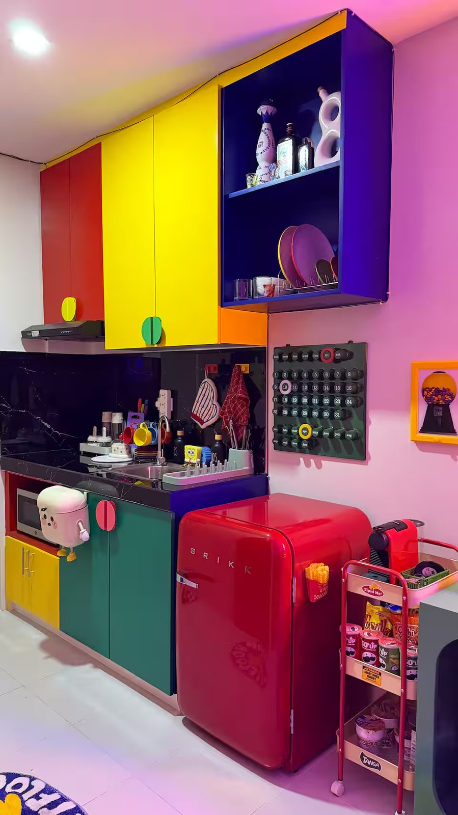 Kitchenette with primary-color block cabinets, red mini fridge, marshmallow magnet and pegboard