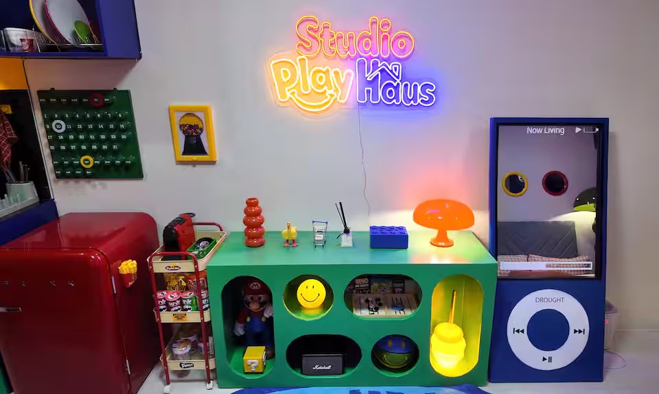 Studio PlayHaus pink neon sign above colorful arcade console with green retro buttons