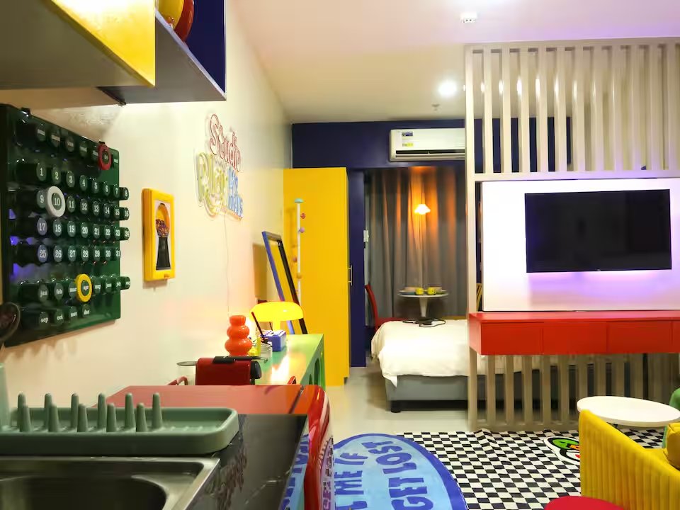 Living room TV mounted on cobalt accent panel with yellow door and checker floor